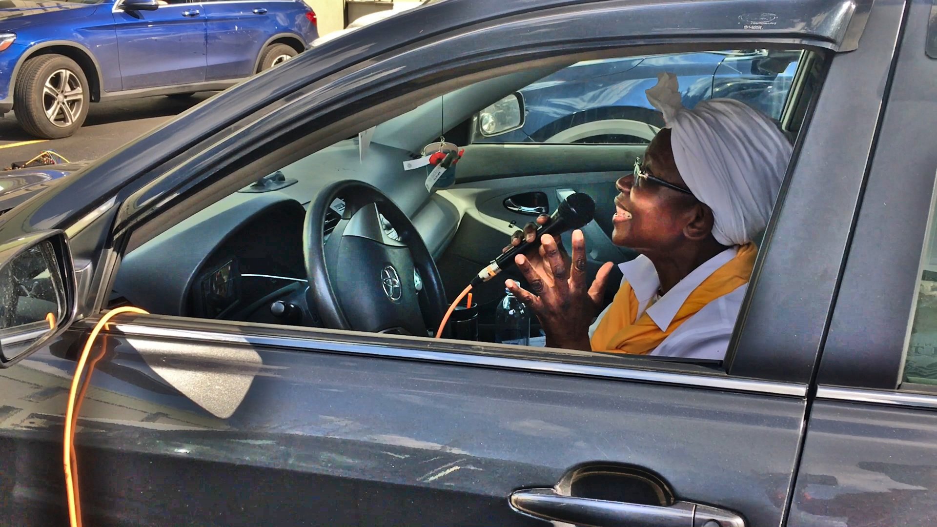 Woman sitting in her car singing into microphone