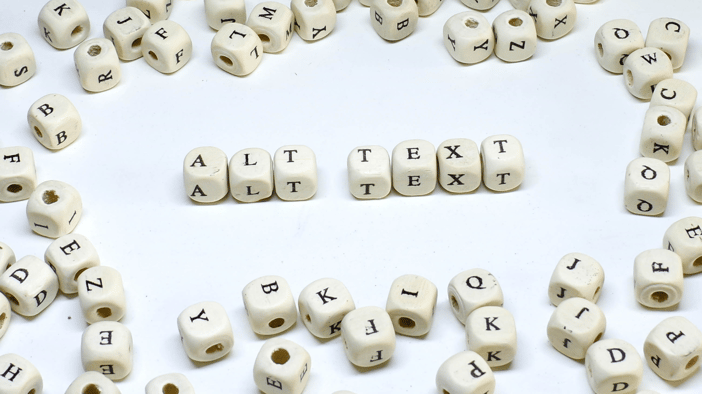 Stock image with dozens of cube-shaped beads scattered across the page; each cube has various letters on each of it's flat sides and 6 cubes sit arranged in a straight line among the scattered beads spelling out "ALT TEXT"