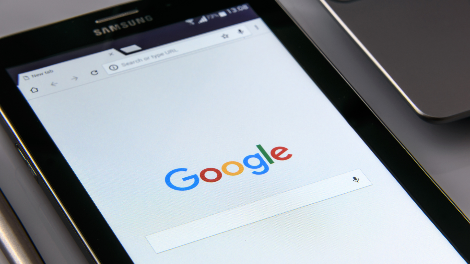 A closely cropped photo of a tablet screen with the Google logo and search bar displayed