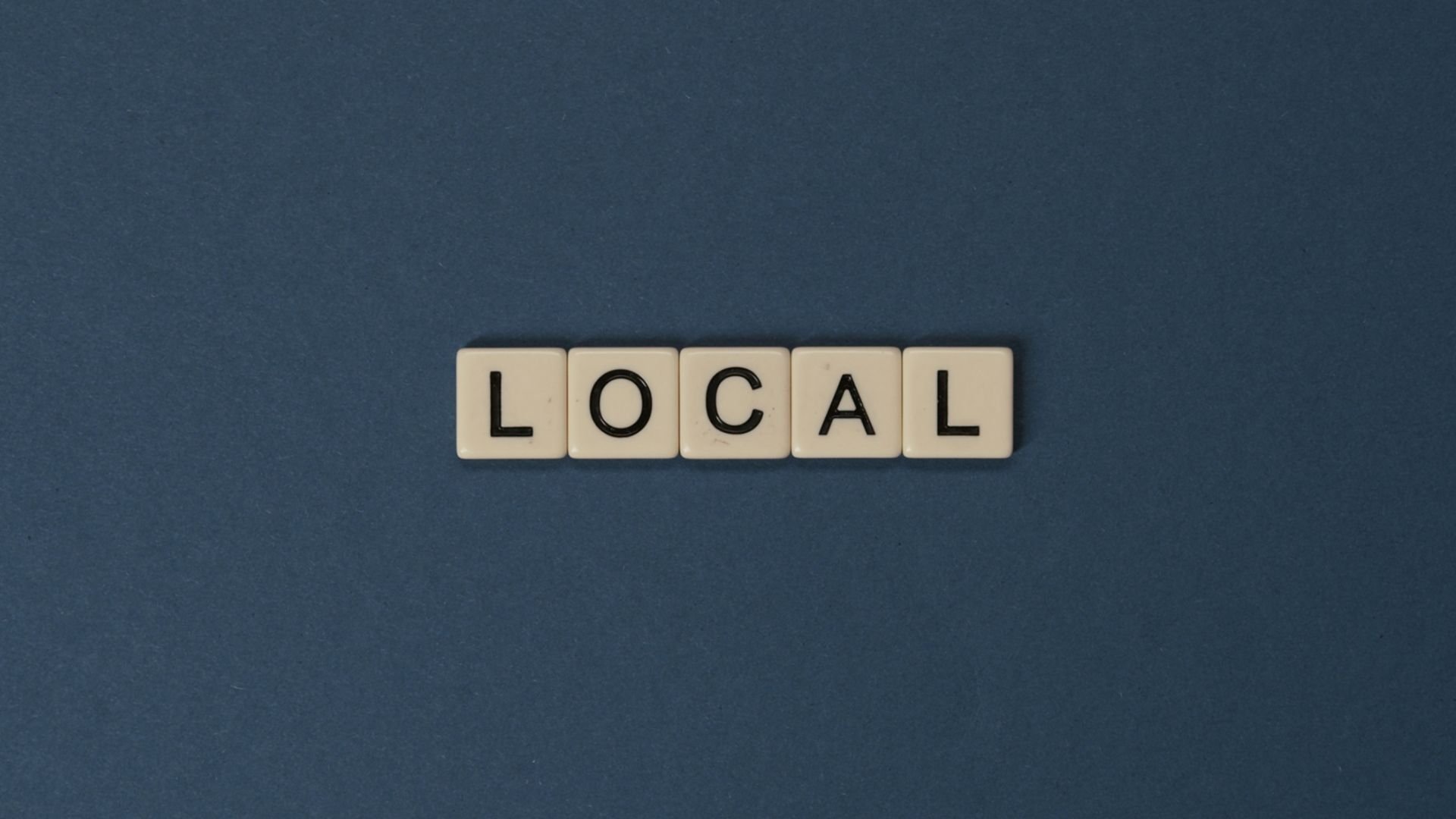 Letter tiles spell “LOCAL” against a dark blue background.