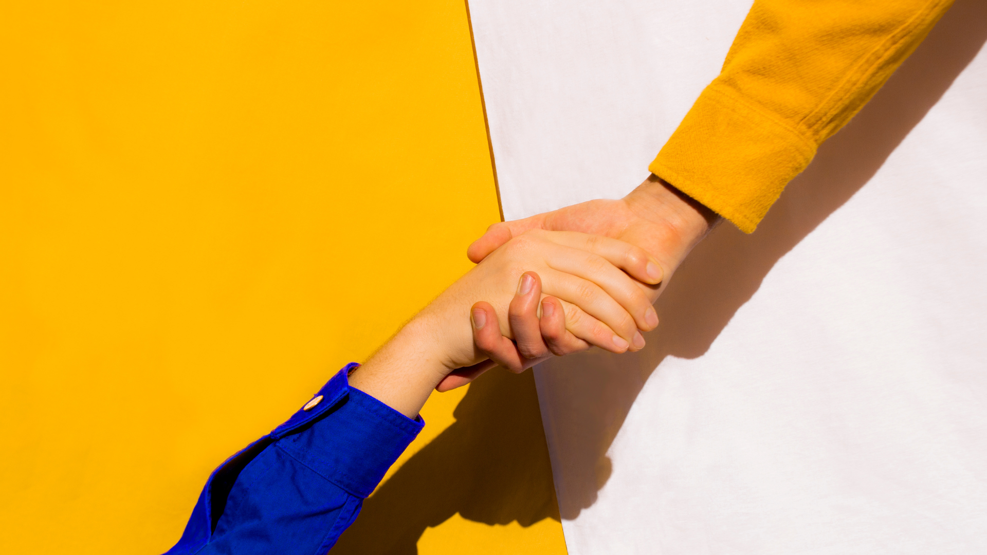 Photo of two hands embraced with one reaching down to pull the other up