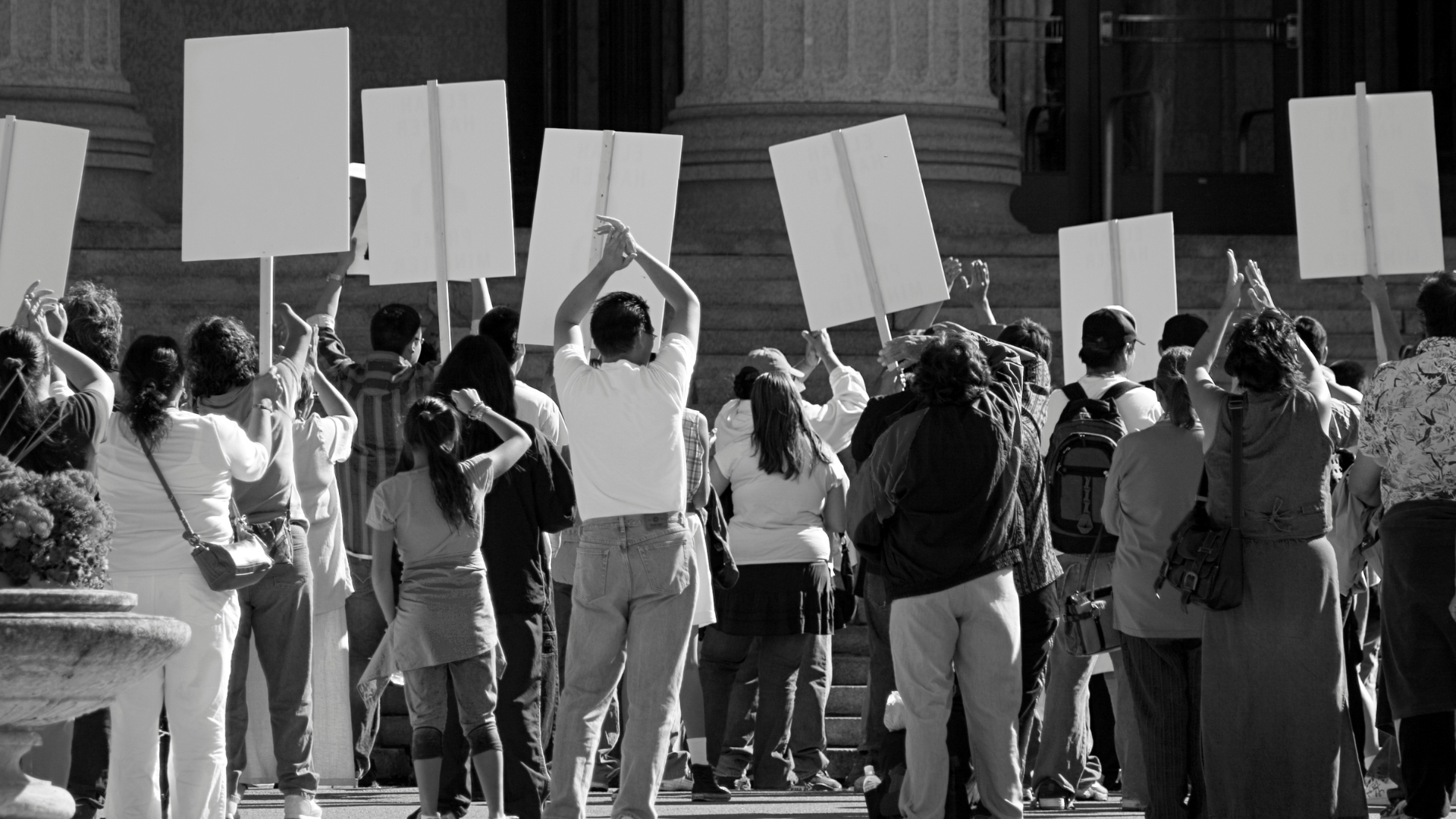 A black and white photo of a large group of people holding up white signs at a protest