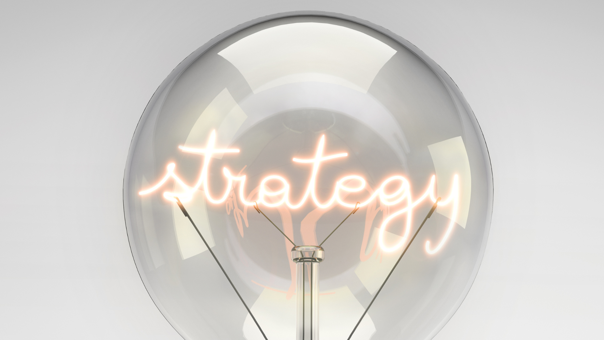 Close-up of a glowing light bulb with the word “strategy” written in illuminated script inside.