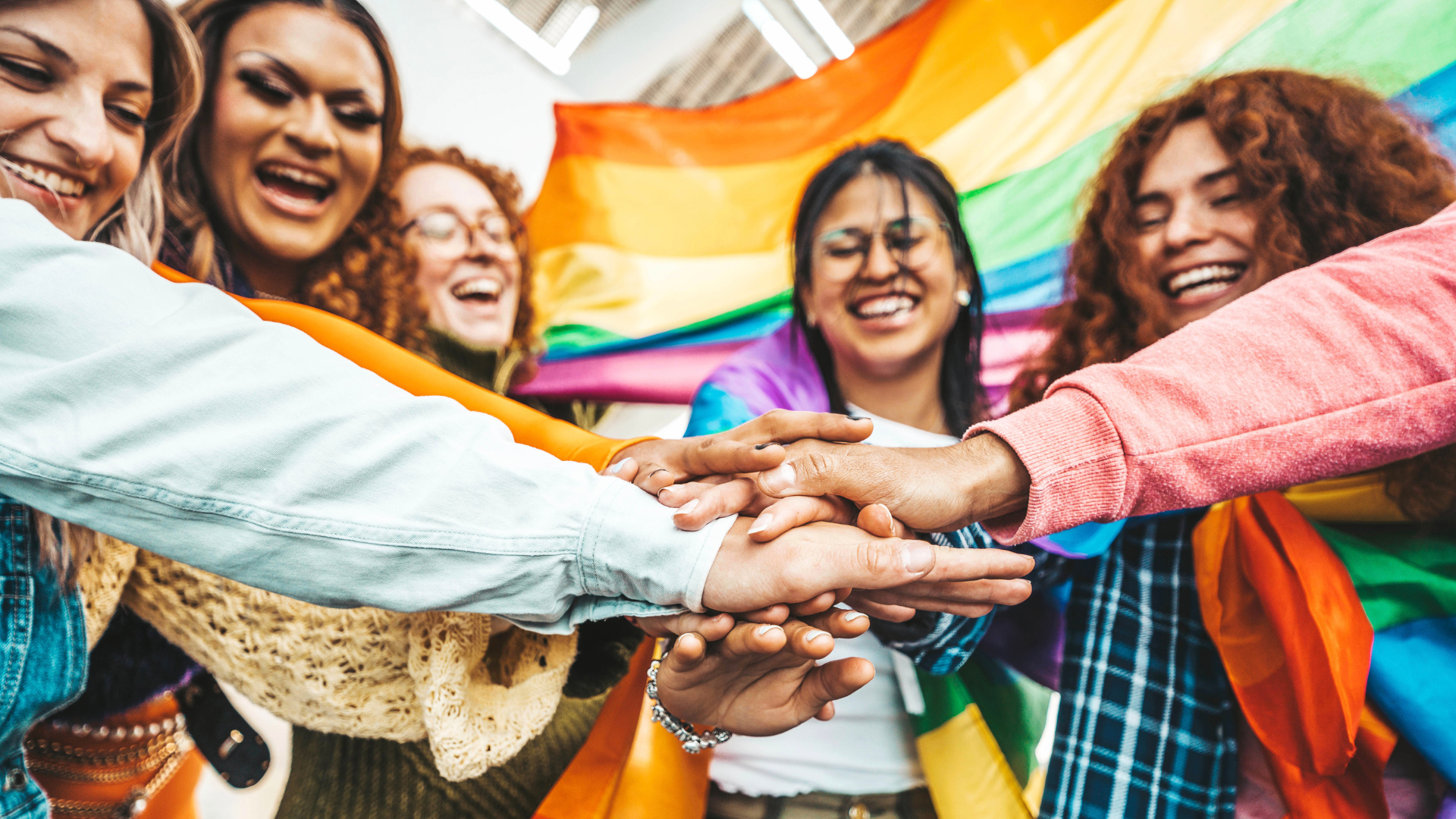 Photo of diverse group of people smiling as they stack hands