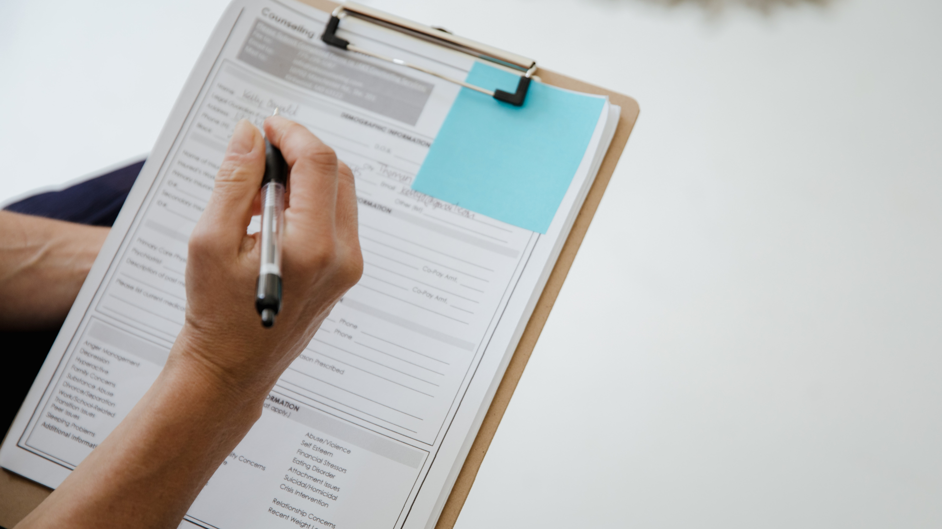 Photo of a hand holding a pen above a survey on a clipboard
