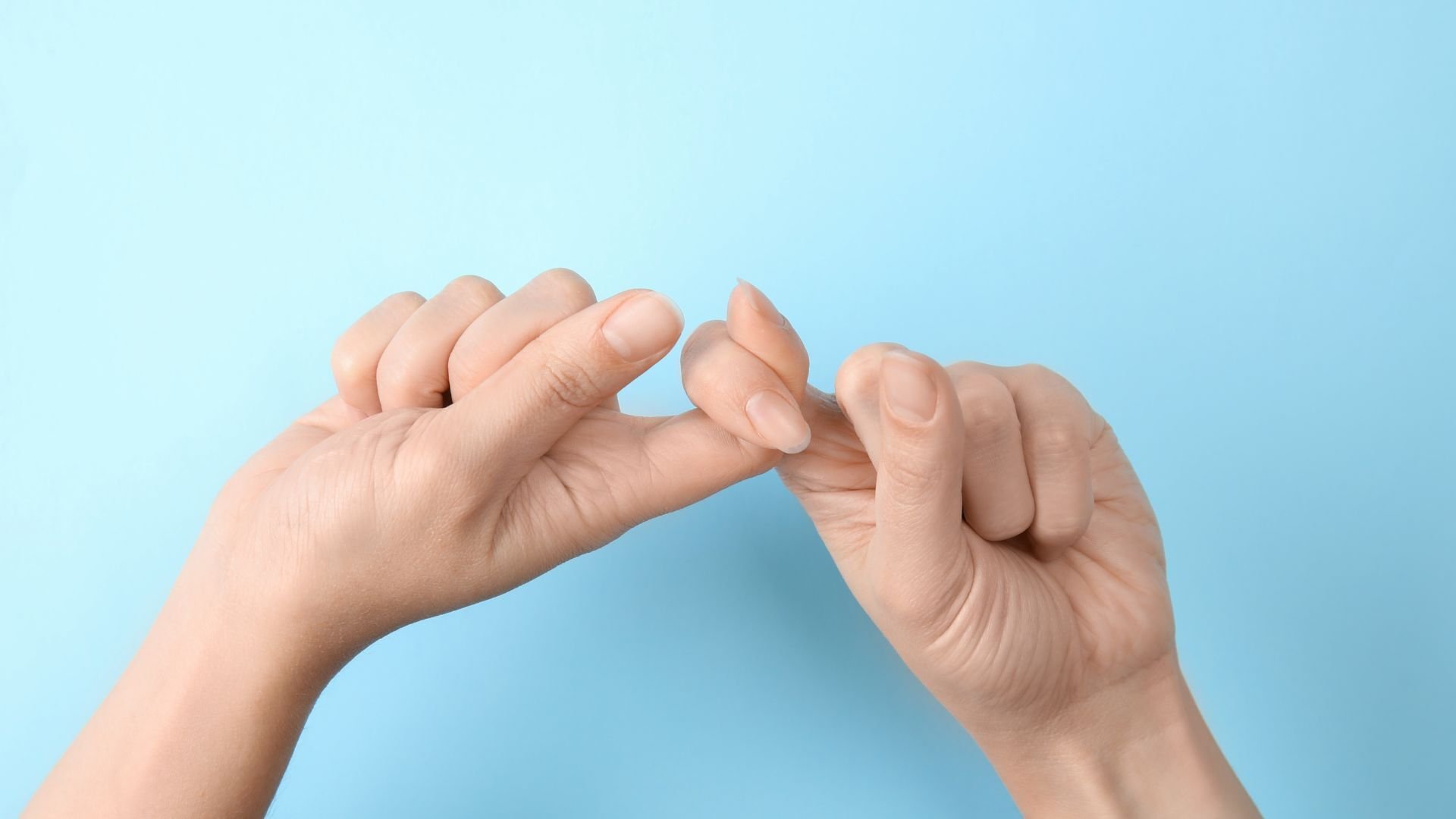 Stock photo of hands doing the ASL sign for "friend" against a light blue background