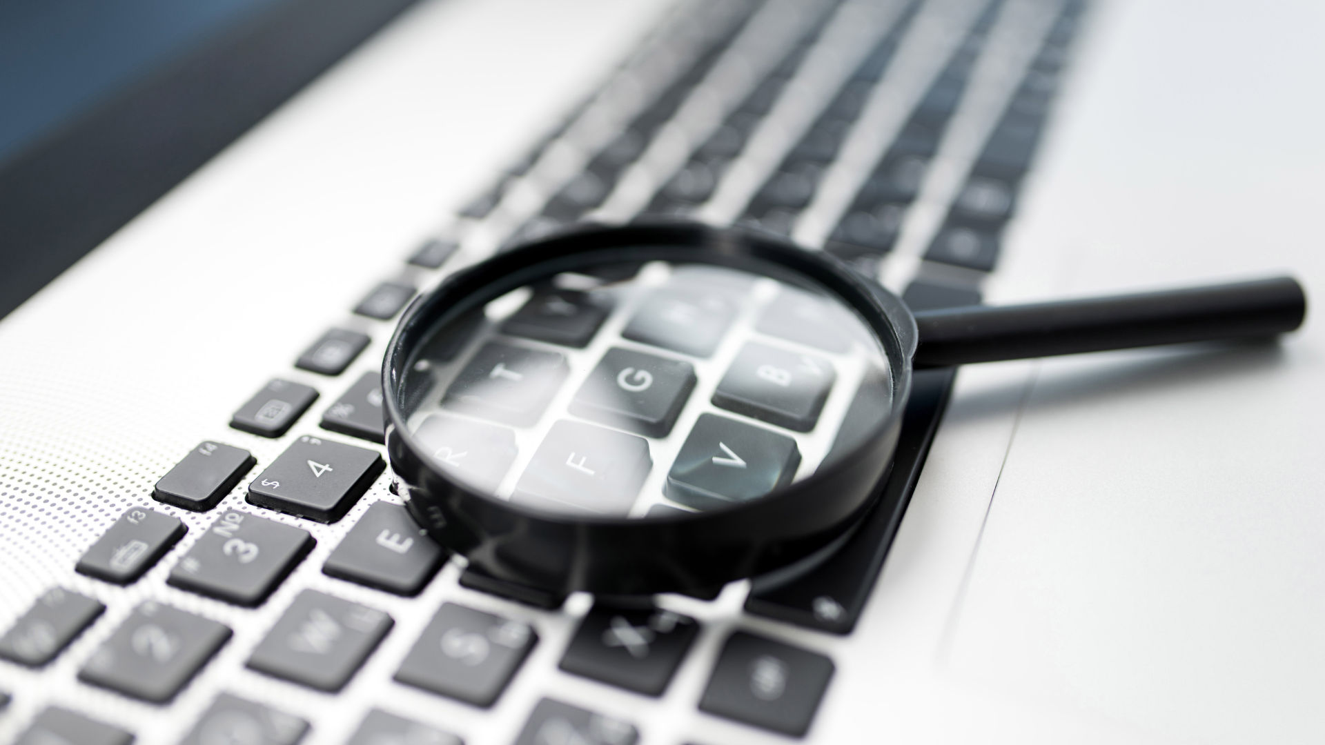 Close-up photo of a magnifying glass laying on a computer keyboard