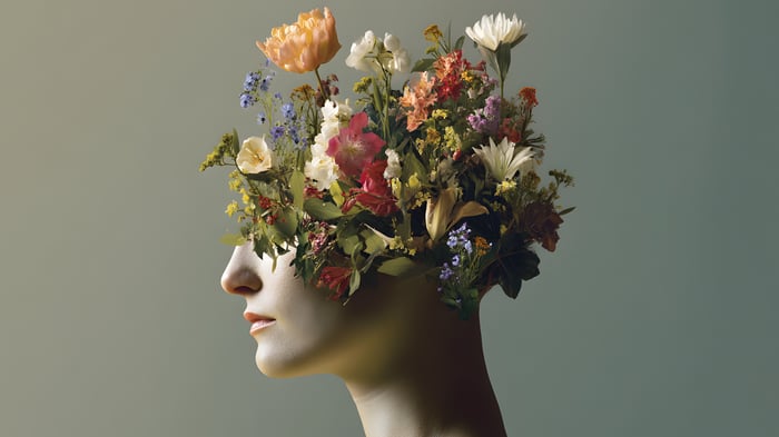 Profile of a person with their head filled with a vibrant arrangement of flowers, creating a surreal, artistic image that suggests creativity, growth, and imagination.