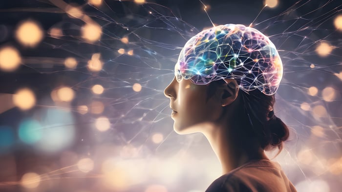 Profile of a person with a glowing, semi-transparent brain overlaid with colorful neural connections and light trails, symbolizing thought, intelligence, or neural activity.