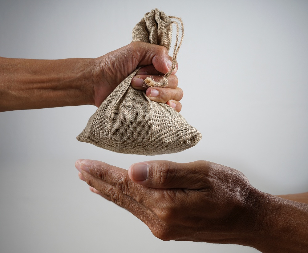 A donor giving a bag of money