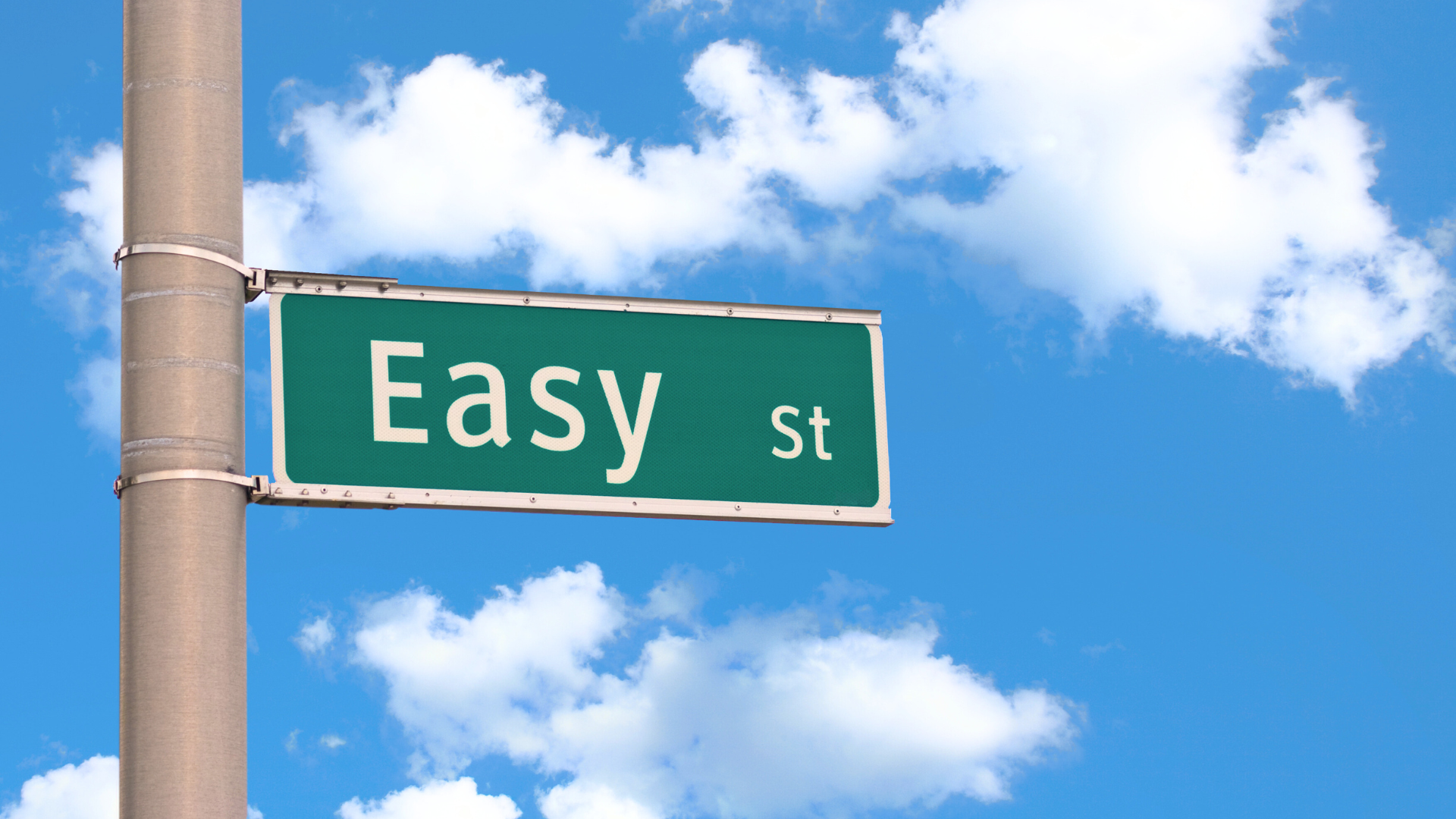 A photo of a brown street pole with a green street sign with the name "Easy St" in white letters against a blue sky with white puffy clouds