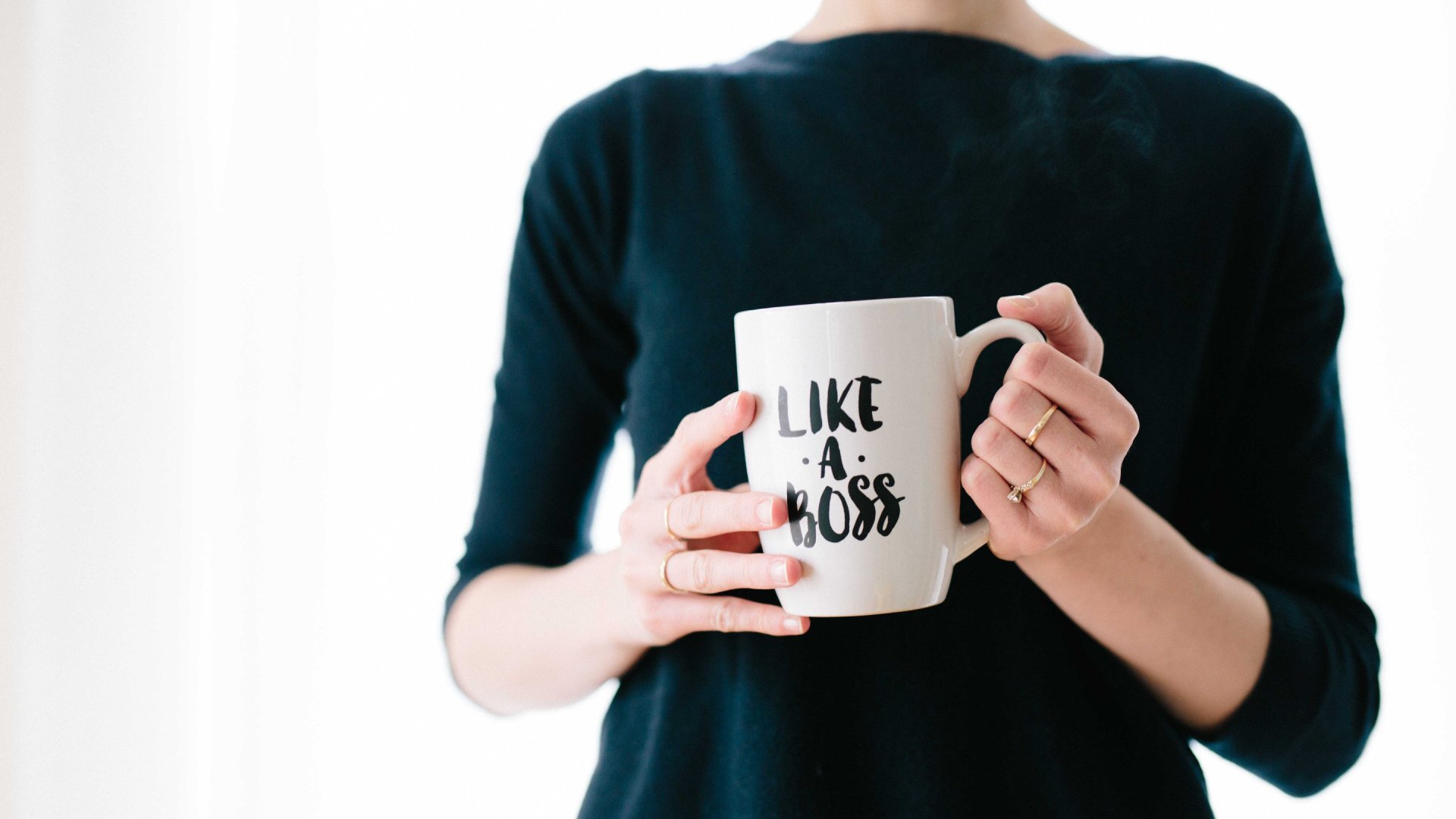Person holding a coffee mug with text on it that says "like a boss"