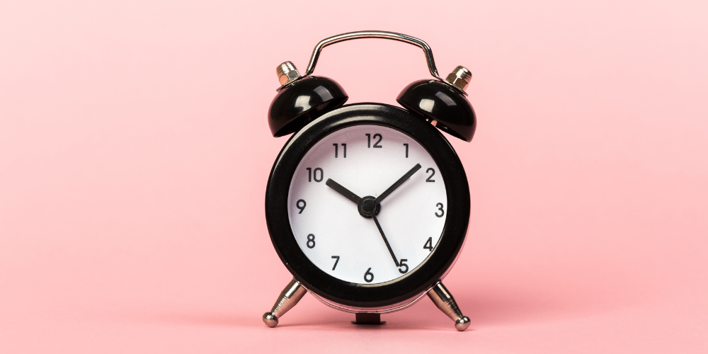 Black retro alarm clock on a pink background