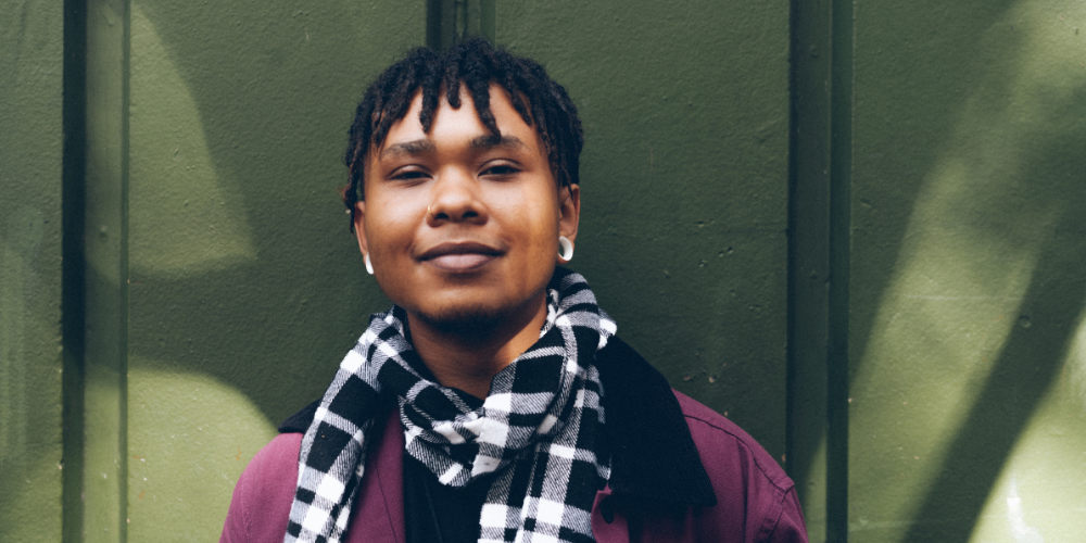 Transgender man with scarf against green wall