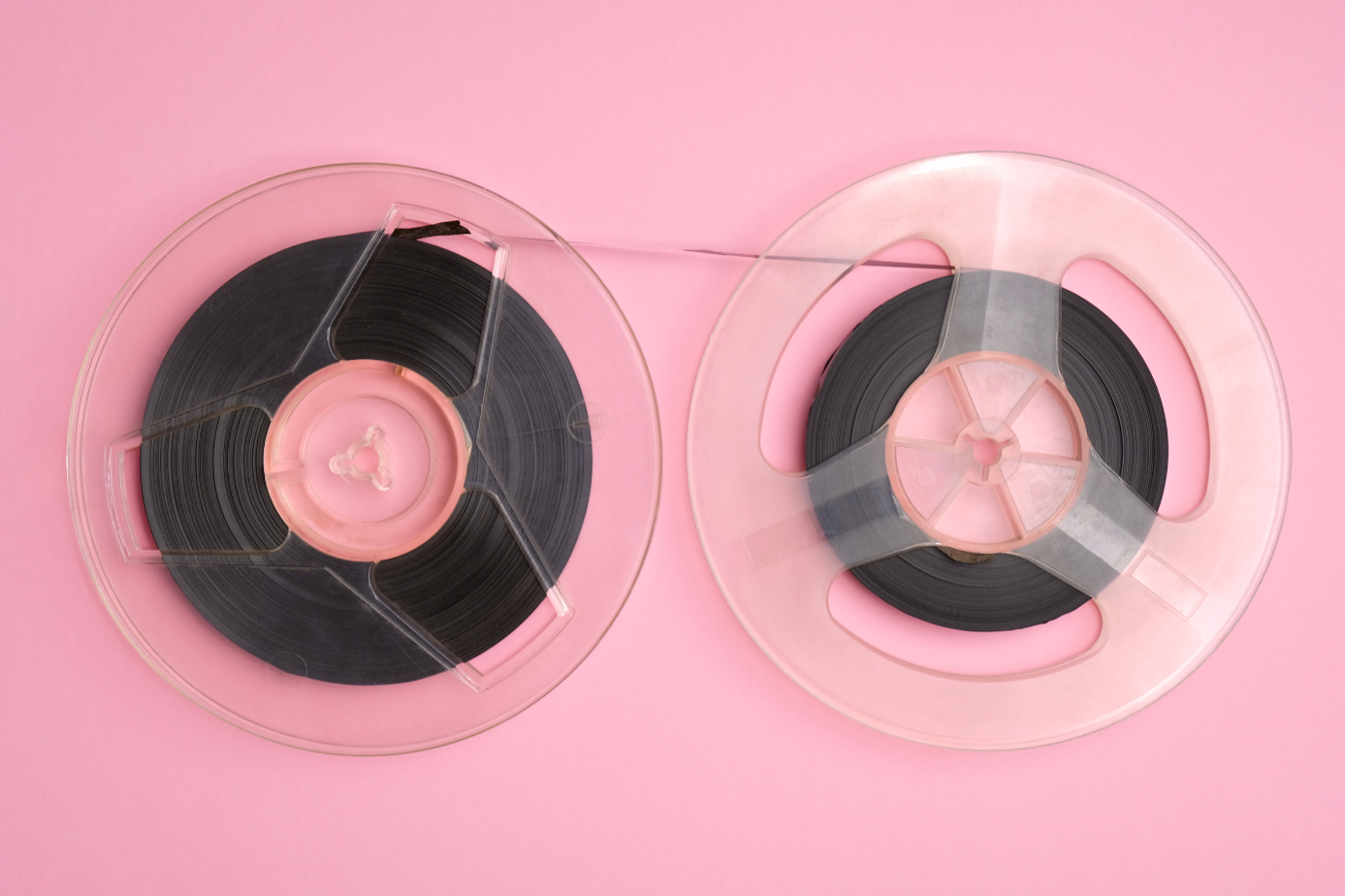 Two plastic transparent reels, side by side, with tape spooled on one reel and connected to the other reel