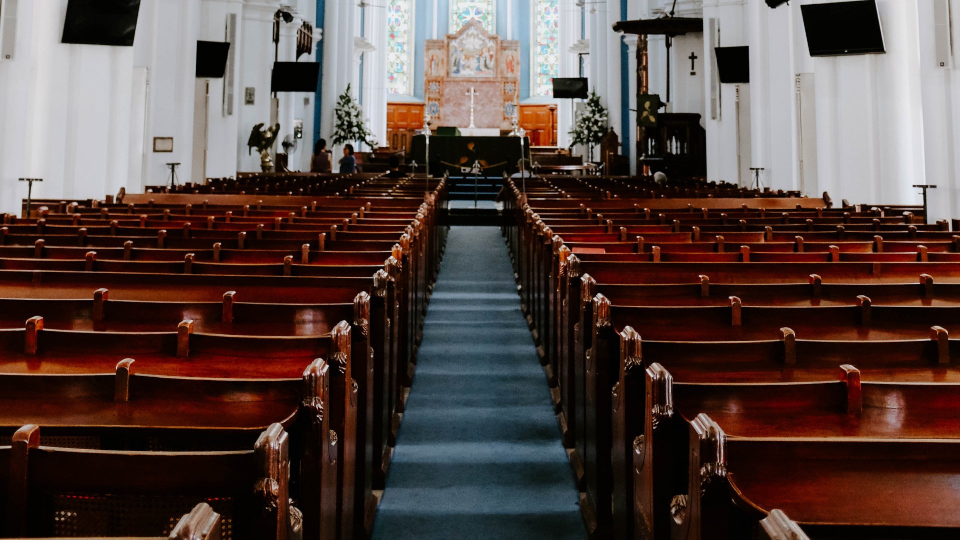 Interior of a church with rows of empty church pews from the back