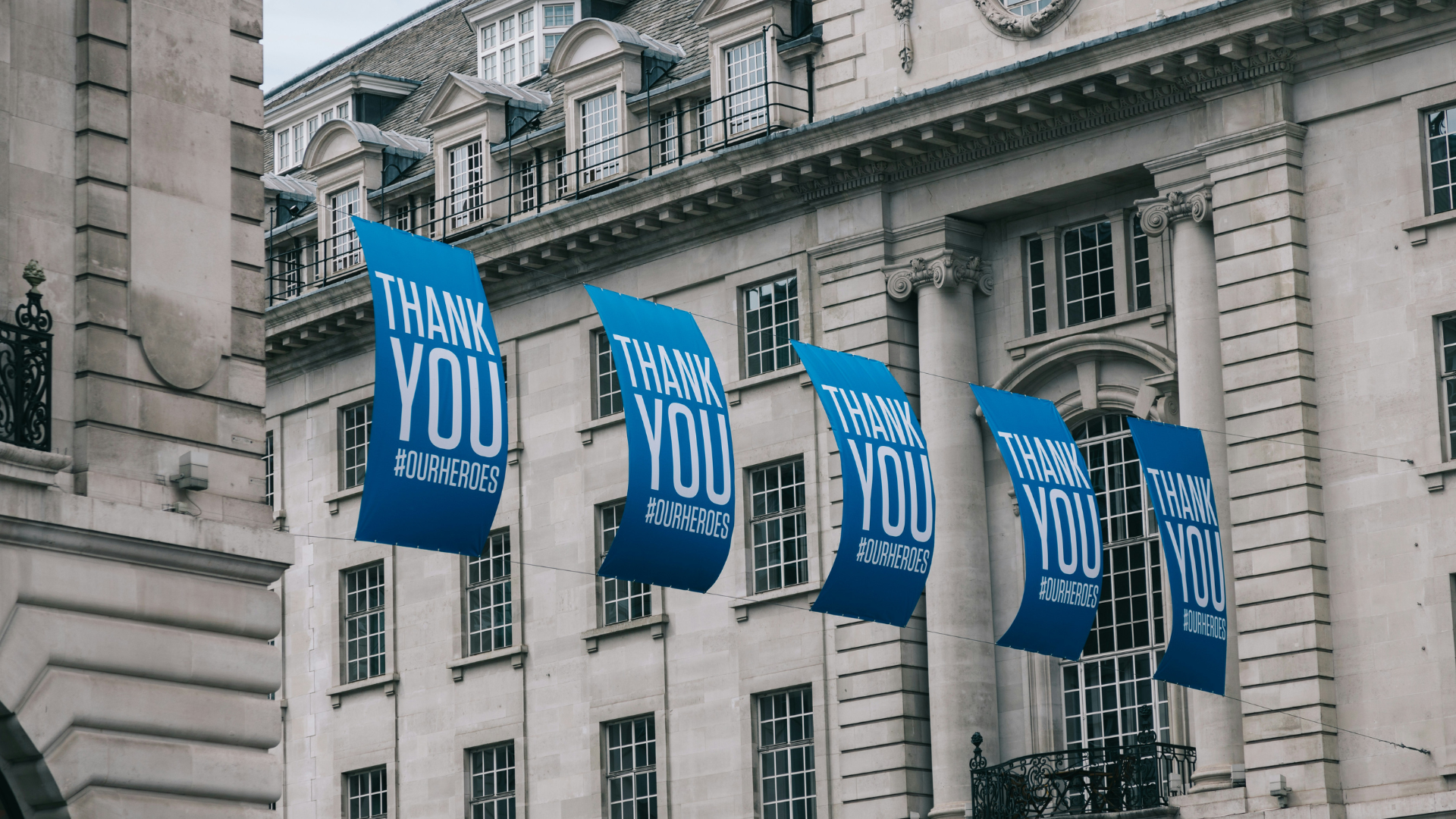 blue and white banners hanging from a building with the text thank you