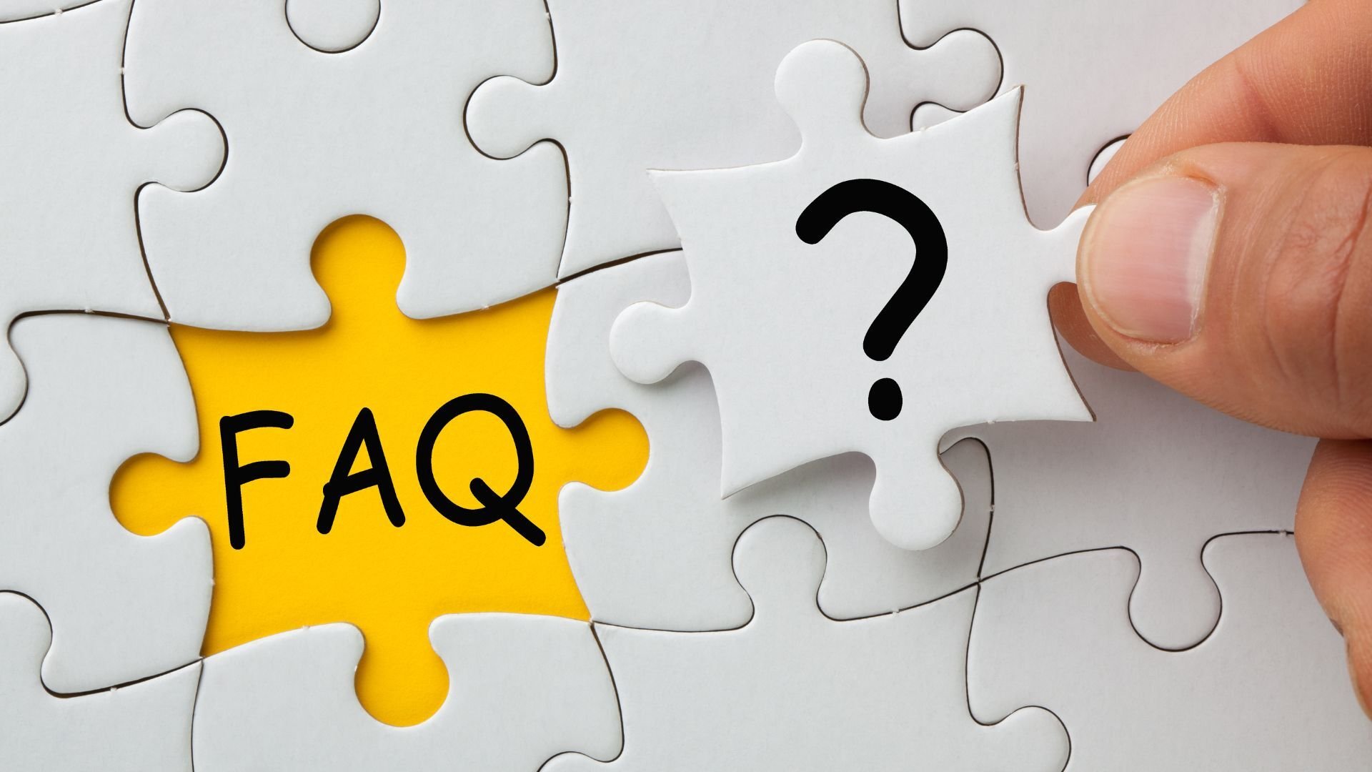 a close up of a hand placing the last piece of a puzzle which will cover up a yellow background with faq written in black font