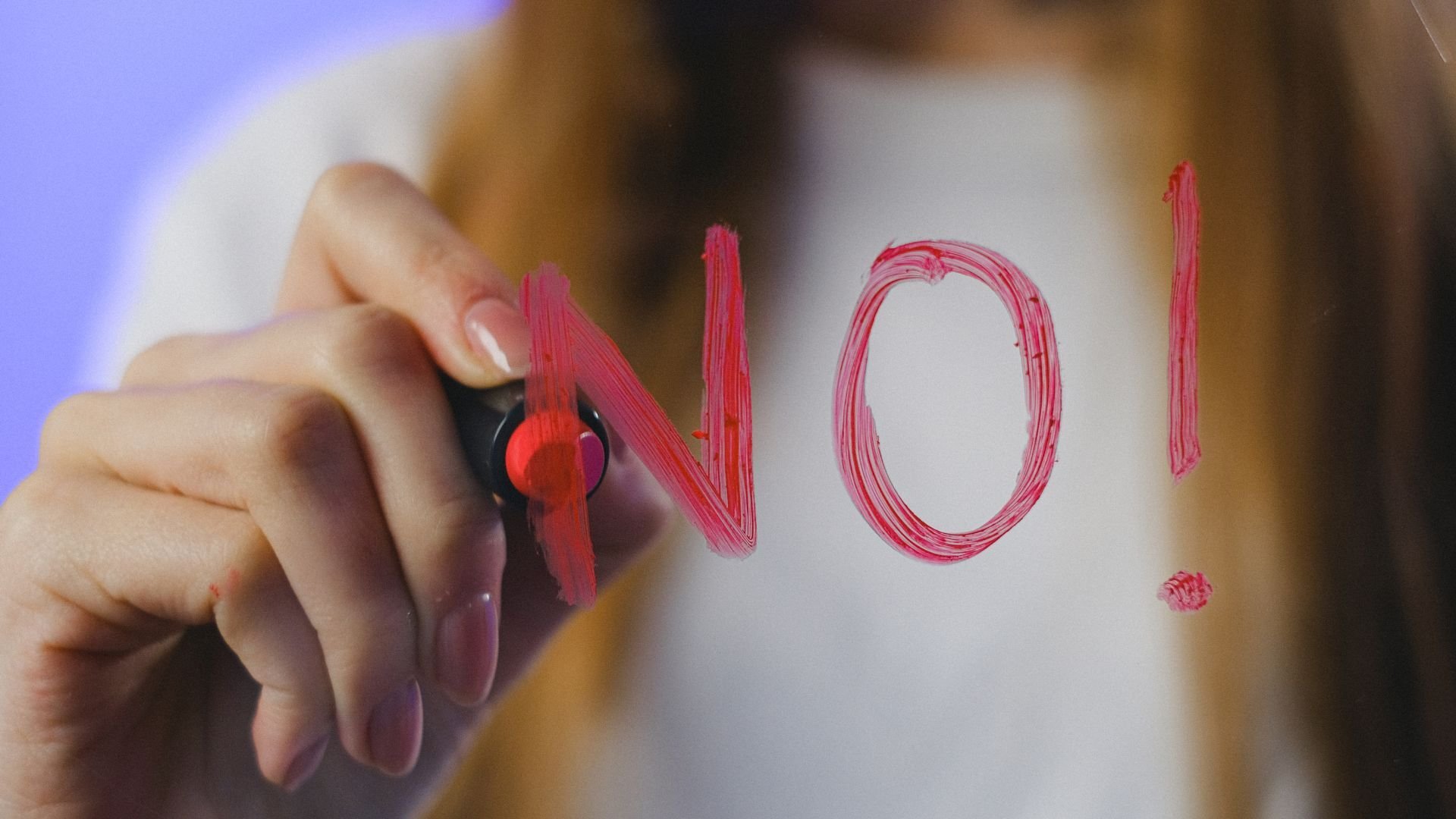 female writing no with red lipstick on a mirror