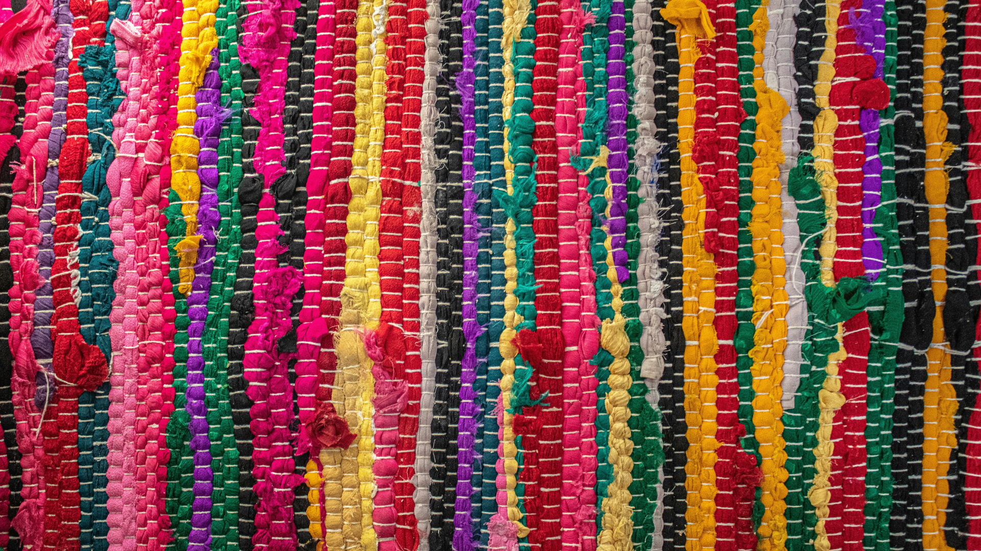 close up photo of a handwoven rug made of different strands or colored yarn