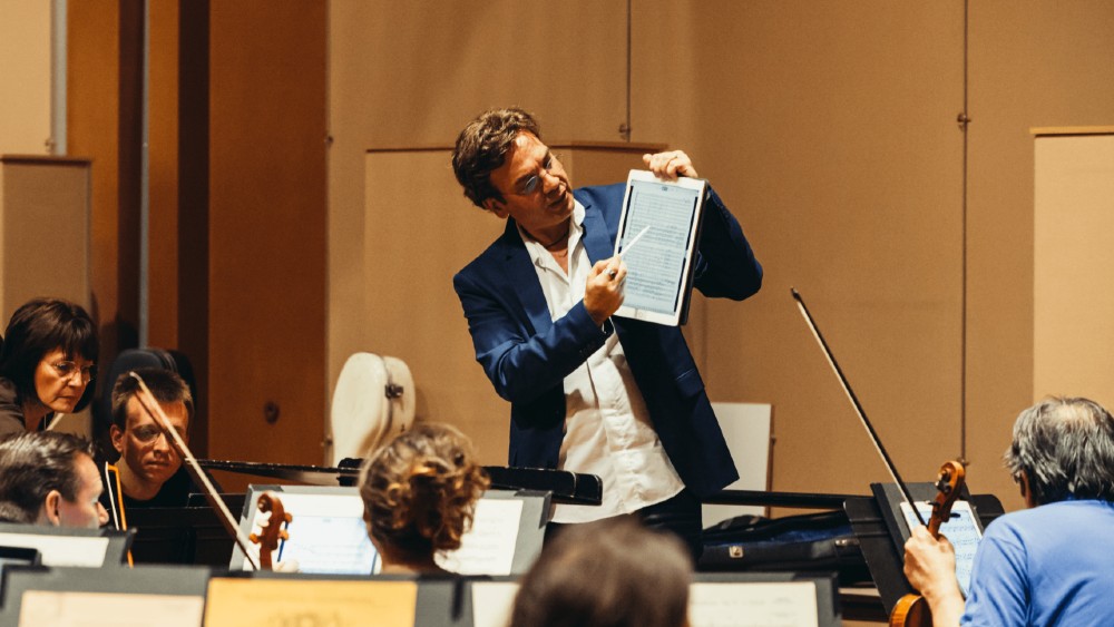 conductor showing digital score to musicians