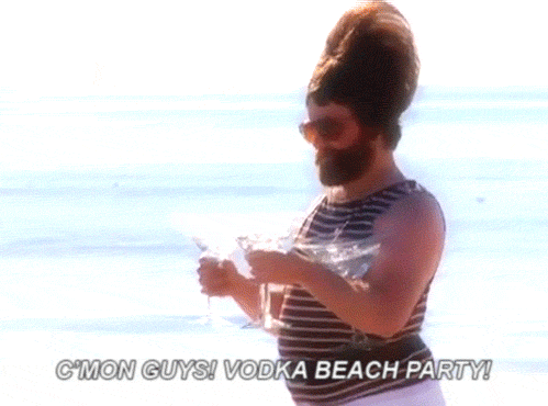 GIF of actor Zach Galifianakis walking along a beach while carrying three large martinis that are spilling as he steps. Text on the GIF reads, "C'mon guys! Vodka beach party!"