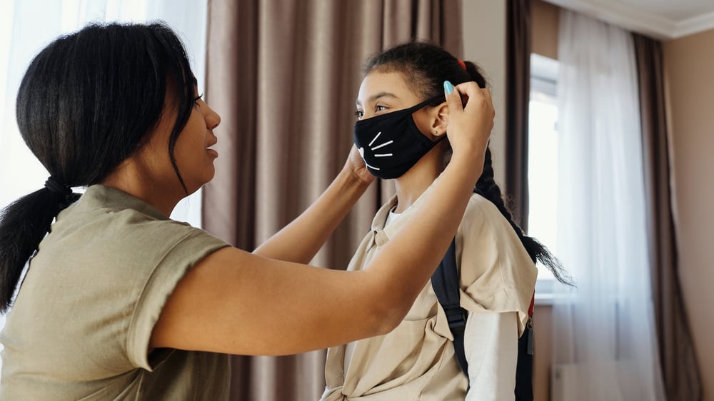 Parent putting mask on child