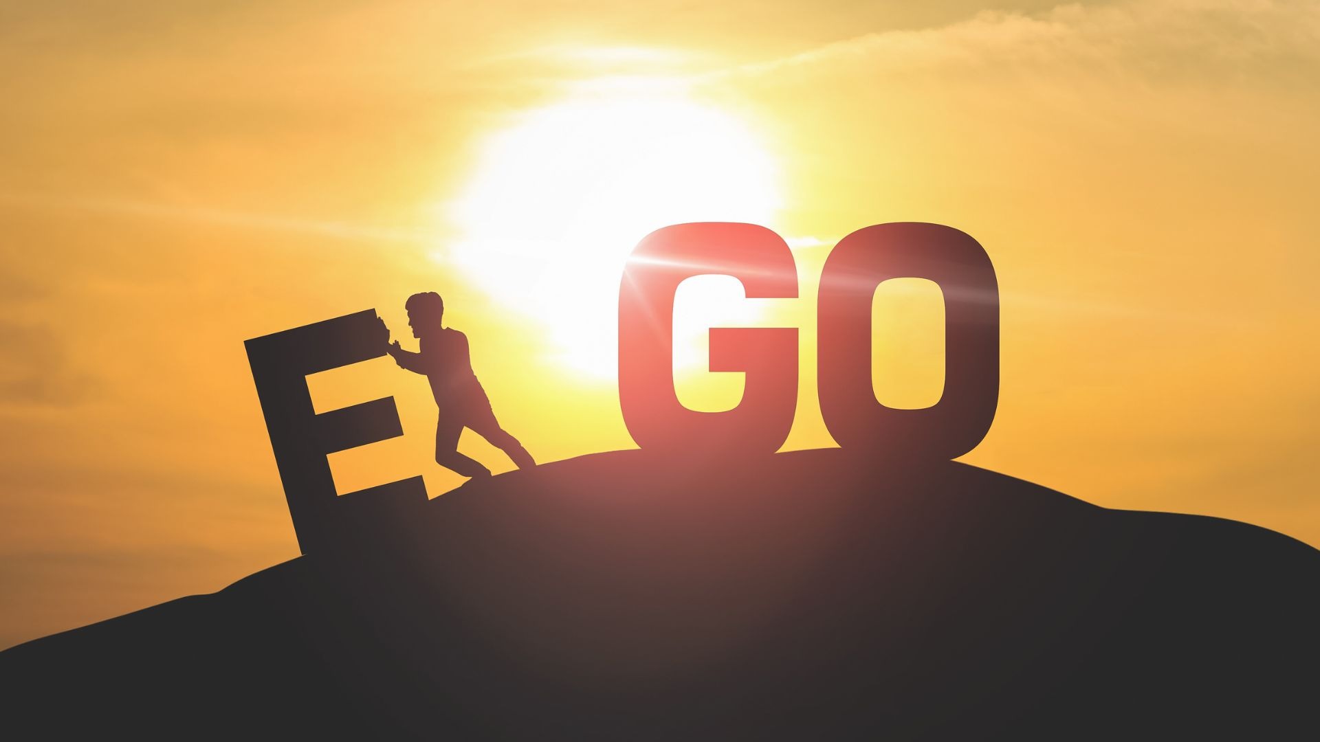 Silhouette of a person pushing the letter “E” downhill away from the word “GO” at sunrise, symbolizing overcoming ego or personal growth.
