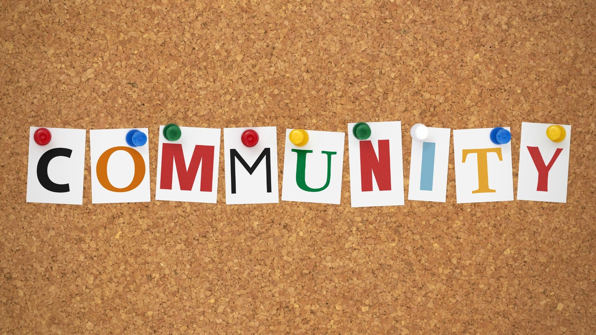 A cork board with the word "Community" pinned on it